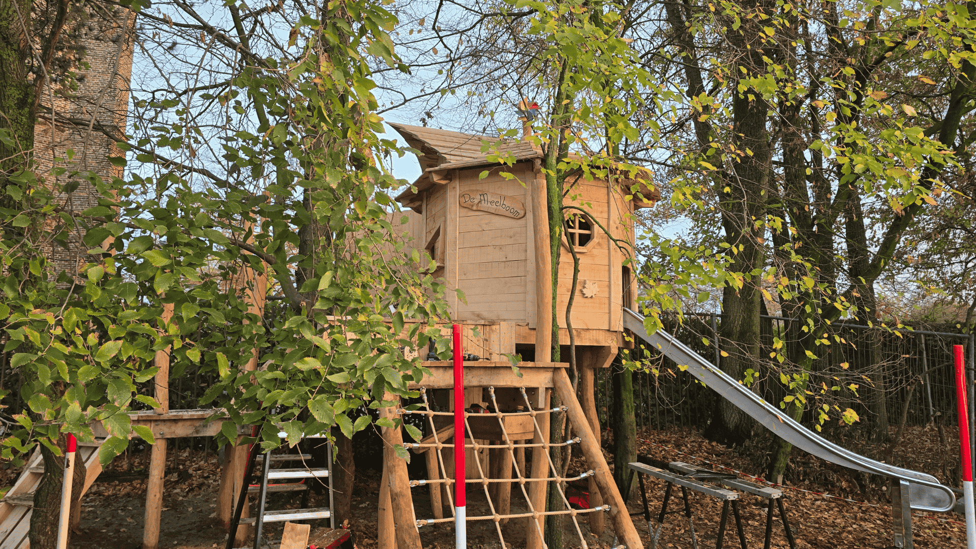 een boomhut die nog in aanbouw is een boomhut voor op het schoolplein met klimnet, glijbaan en een bordes trap